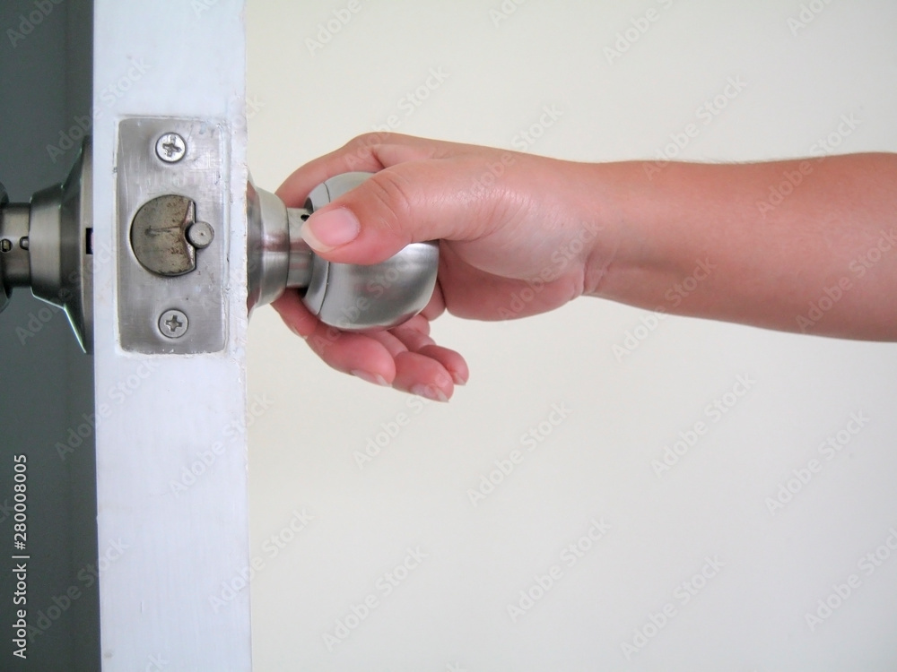 The hand is twisting the knob to open the door. Open the whitedoor with the  keys. Door knob with a key. Stock Photo | Adobe Stock