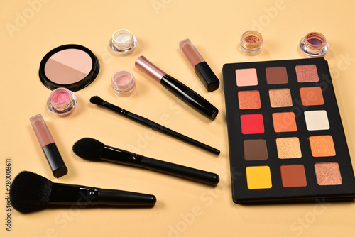 Professional makeup products with cosmetic beauty products, eye shadows, pigments, lipsticks, brushes and tools on beige background. Space for text or design.