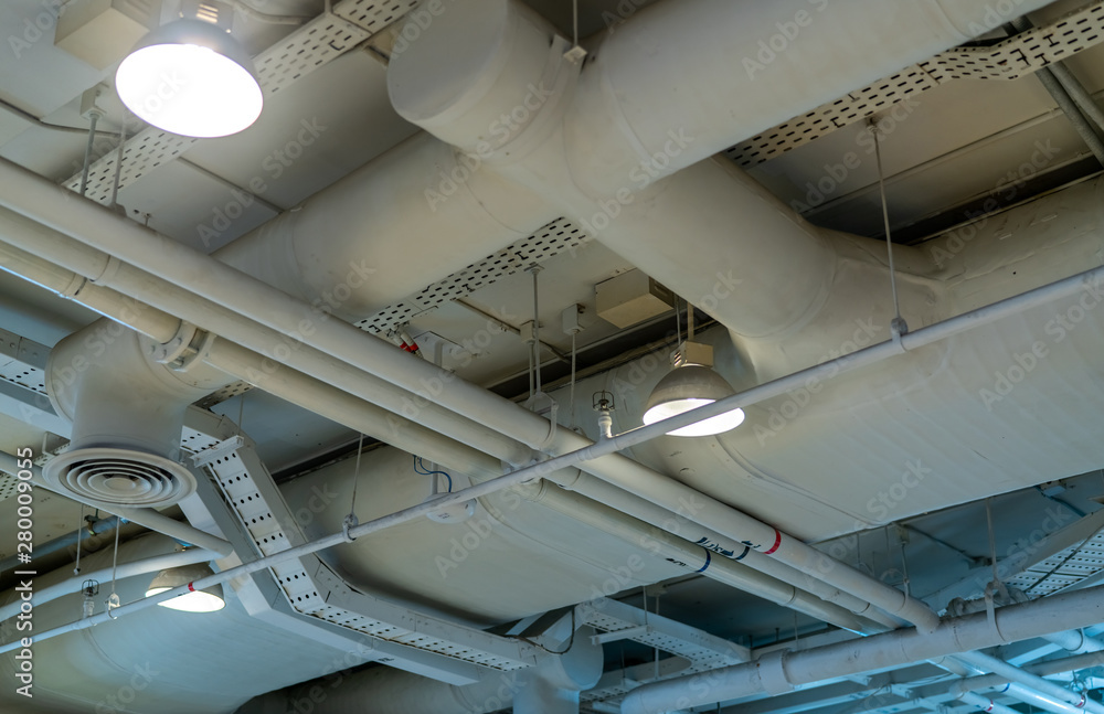 Air duct, wiring and plumbing in the mall. Air conditioner pipe, wiring pipe, and plumbing pipe system. Building interior concept. Ceiling lamp light with opened light. Interior architecture concept.