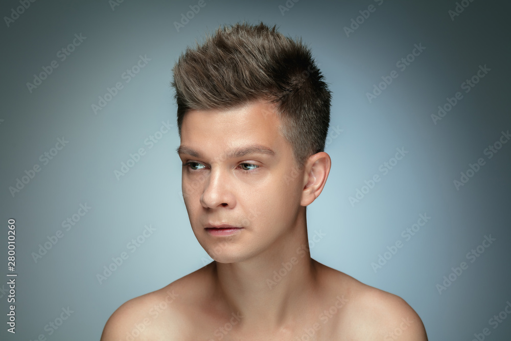 Portrait of shirtless young man isolated on grey studio background. Caucasian healthy male model looking at side and posing. Concept of men's health and beauty, self-care, body and skin care. Portrait of shirtless young man isolated on grey studio background. Caucasian healthy male model looking at side and posing. Concept of men's health and beauty, self-care, body and skin care.