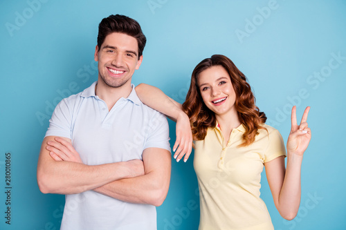 Photo of funny pair v-sign symbol hands cheerful say hi buddies lean elbow shoulder wear casual t-shirts isolated blue background