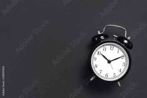 Black retro alarm clock on gray dark background top view Flat lay copy space. Minimalistic background, concept of time, deadline, time to work, morning
