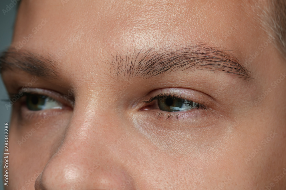 Obraz premium Close-up portrait of young man's face isolated on grey studio background. Caucasian male model looking at side and posing. Concept of men's health and beauty, self-care, body and skin care.
