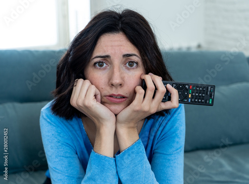 Bored woman changing TV channels with remote control photo