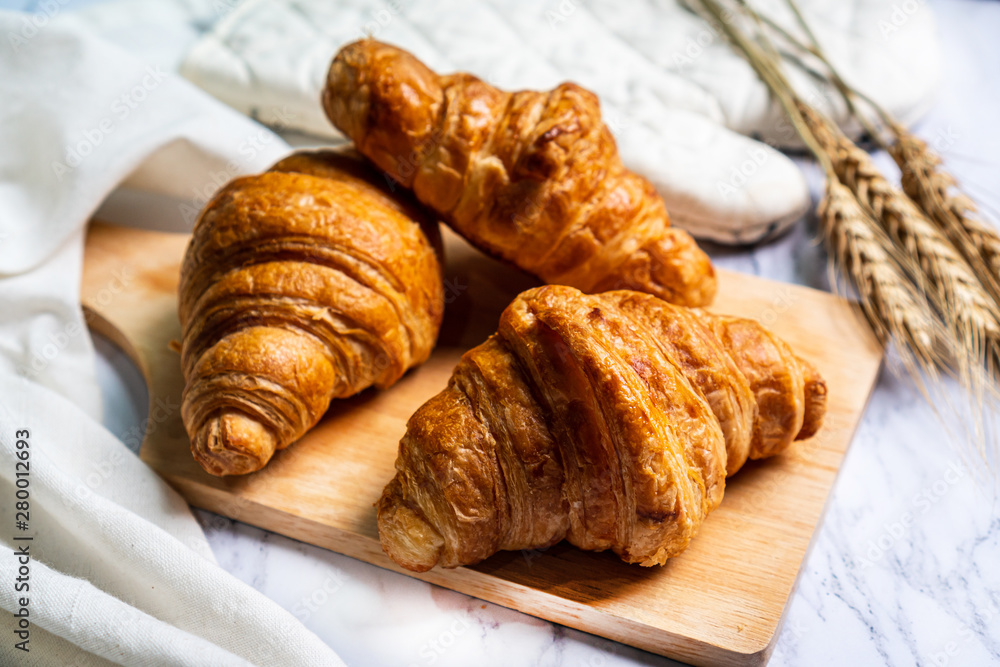freshly baked croissants on wooden cutting board.