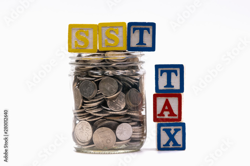 Stack of coin with alphabet block witten with tax related such as gst, sst and vat photo