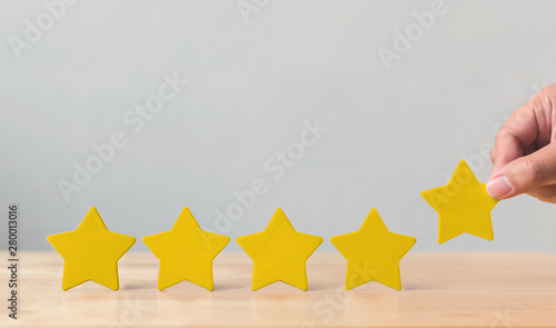 Hand putting wooden five star shape on table. The best excellent business services rating customer experience concept