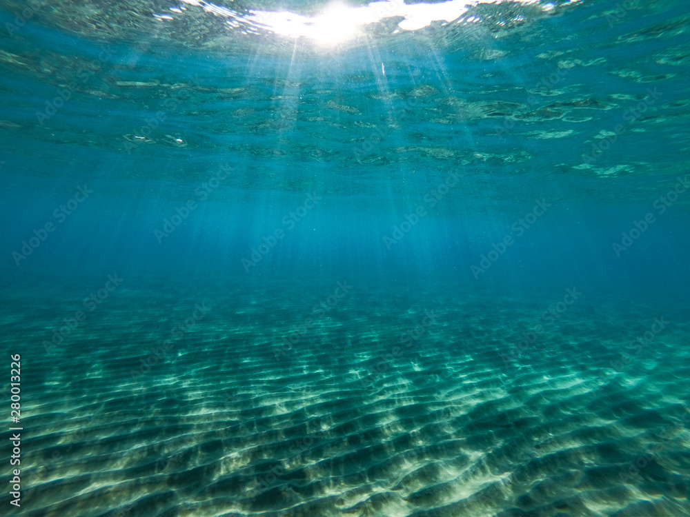 Underwater view of the rocks, sand and stones. The sandy and rocky bottom of the sea with some sun rays. Underwater view of the rocks, sand and stones. The sandy and rocky bottom of the sea with some sun rays.