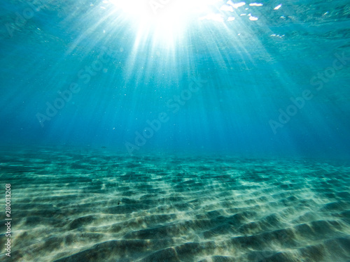 Underwater view of the rocks, sand and stones. The sandy and rocky bottom of the sea with some sun rays. © magdal3na