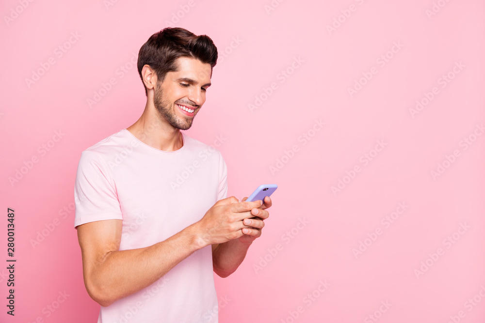 Profile side view portrait of his he nice attractive cheerful cheery concentrated guy holding in hands device web surfing using dating service isolated over pink pastel background Profile side view portrait of his he nice attractive cheerful cheery concentrated guy holding in hands device web surfing using dating service isolated over pink pastel background