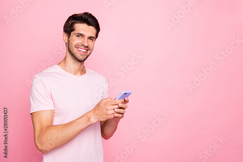 Portrait of his he nice attractive lovely cheerful cheery confident content guy holding in hands device using dating service chatting isolated over pink pastel background © deagreez