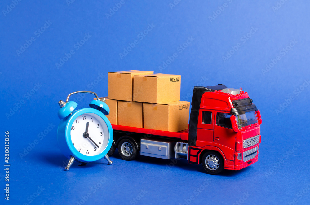A red truck with cardboard boxes and a blue alarm clock. Express delivery  in short time concept. Temporary storage, limited offer and discount.  Optimization of delivery logistics. Transport company Photos | Adobe