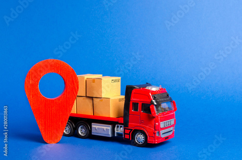 A red truck loaded with boxes and a red pointer location. Services transportation of goods, products, logistics and infrastructure. Transportation company. Location of carriers. Package tracking photo