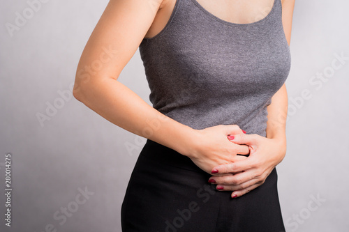 A beautiful woman holding her stomach, symptom of sickness. Stress,  Menstruation, Early pregnancy failure, Diarrhea, Digestive problem, Cervical cancer, Cramp, Stomachache, Unhealthy diet, Gastritis.