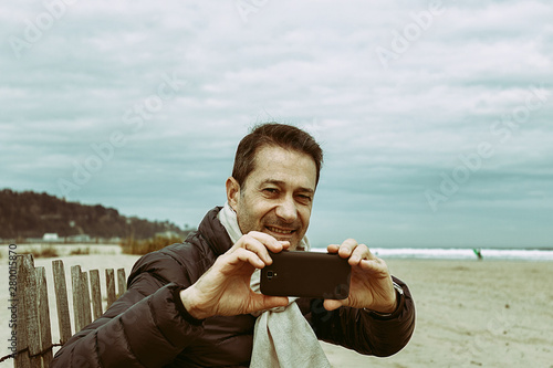 man taking photos on the beach in hendaya, france photo