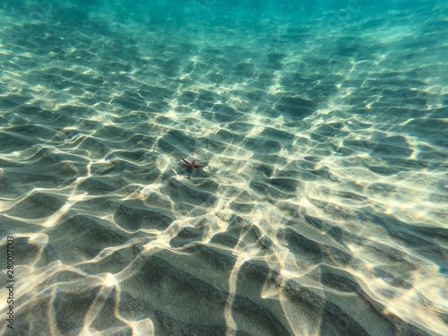 Underwater view of the rocks, sand and stones. The sandy and rocky bottom of the sea with some sun rays.