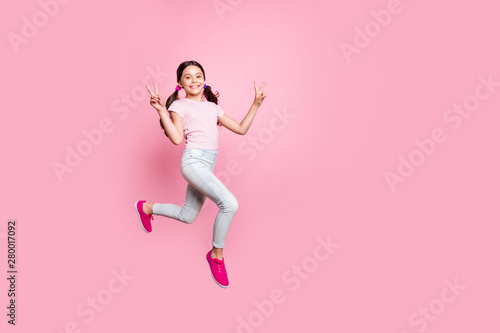 Full length side photo of beautiful little lady jumping high v-sign symbol dressed casual outfit isolated pink background