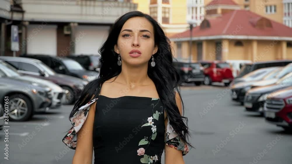 The camera follows a young attractive brunette in the parking lot. The camera follows a young attractive brunette in the parking lot.