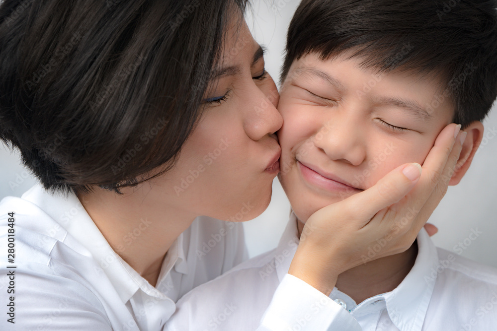 Closeup: Precious moment of a good looking preteen boy, his beautiful mother gently kiss him on the cheek, their eyes closed with happiness. Parenting child, Beloved son, Teen boy and mom, Mom's love. Closeup: Precious moment of a good looking preteen boy, his beautiful mother gently kiss him on the cheek, their eyes closed with happiness. Parenting child, Beloved son, Teen boy and mom, Mom's love.