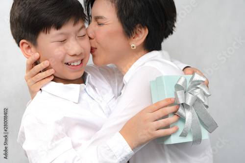 A happy and healthy smart looking asian preteen / teenage boy giving his beautiful Mom a present on Mother's day or birthday. Love expression, Parenting teen, Single mom, Preteen son, Mother and Son.
