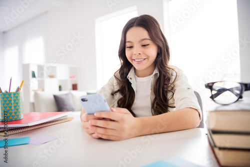Portrait of her she nice attractive charming cute cheerful cheery wavy-haired pre-teen girl having rest relax pause break using 5g app browsing internet online in light white interior room library
