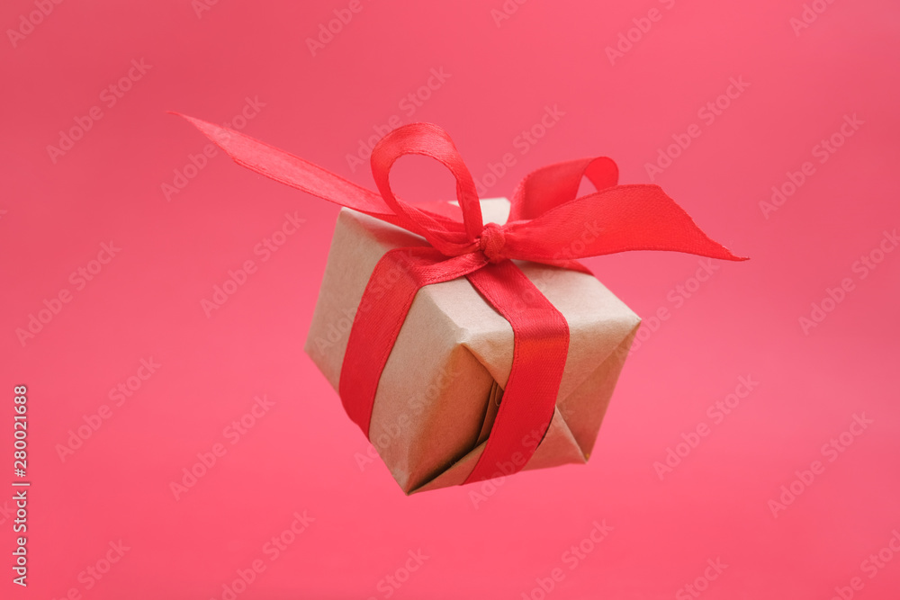 Gift box with red ribbon on red background. zero gravity. levitation. milimalism. Concept sales, shopping, christmas holidays and birthday