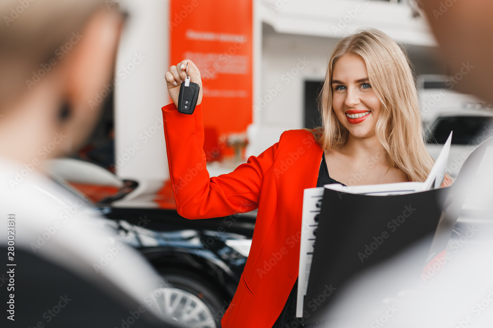 Car dealer showing a key in her hand and wide smiling closeup- Image Car dealer showing a key in her hand and wide smiling closeup- Image