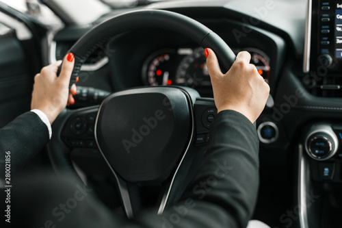 Female hands holding a steering wheel in car salon - Image