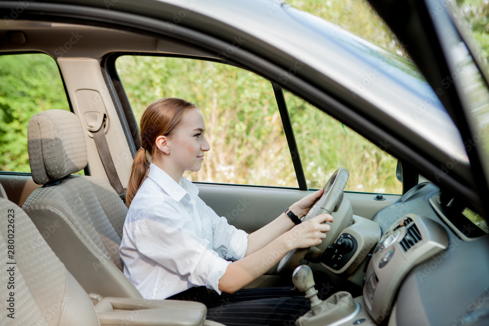 Close up portrait of pleasant looking female with glad positive expression, being satisfied with unforgettable journey by car, sits on driver s seat. People, driving, transport concept Close up portrait of pleasant looking female with glad positive expression, being satisfied with unforgettable journey by car, sits on driver s seat. People, driving, transport concept