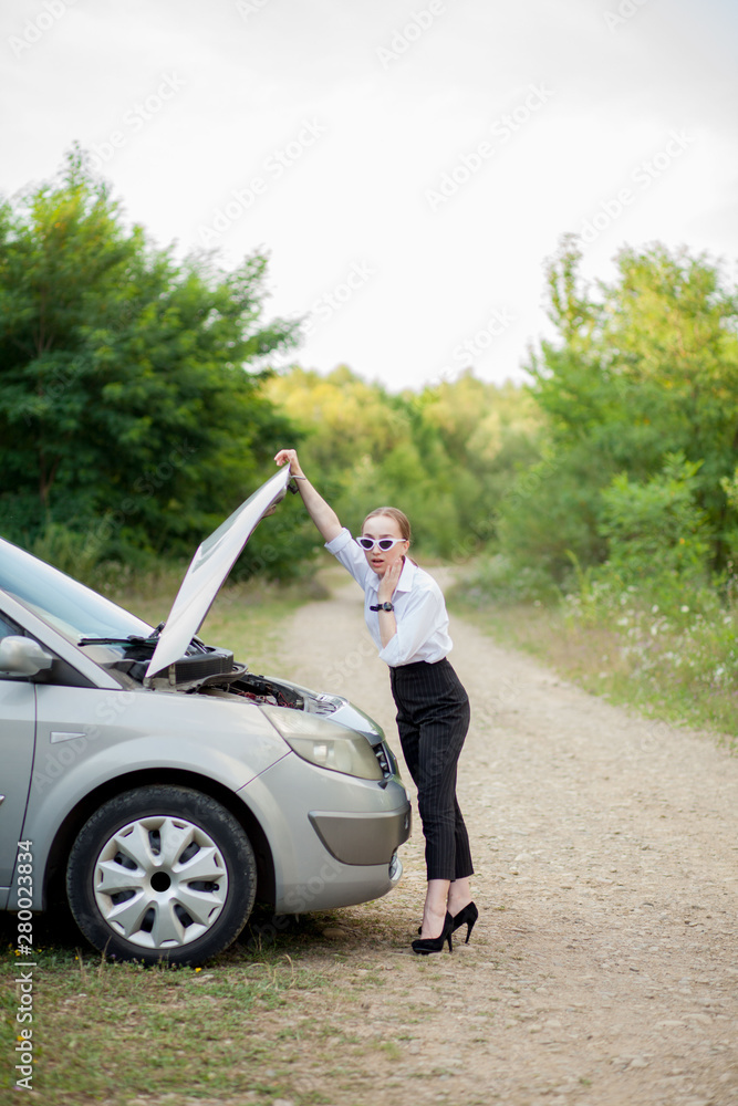 Young woman by the roadside after her car has broken down She opened the hood to see the damage Young woman by the roadside after her car has broken down She opened the hood to see the damage