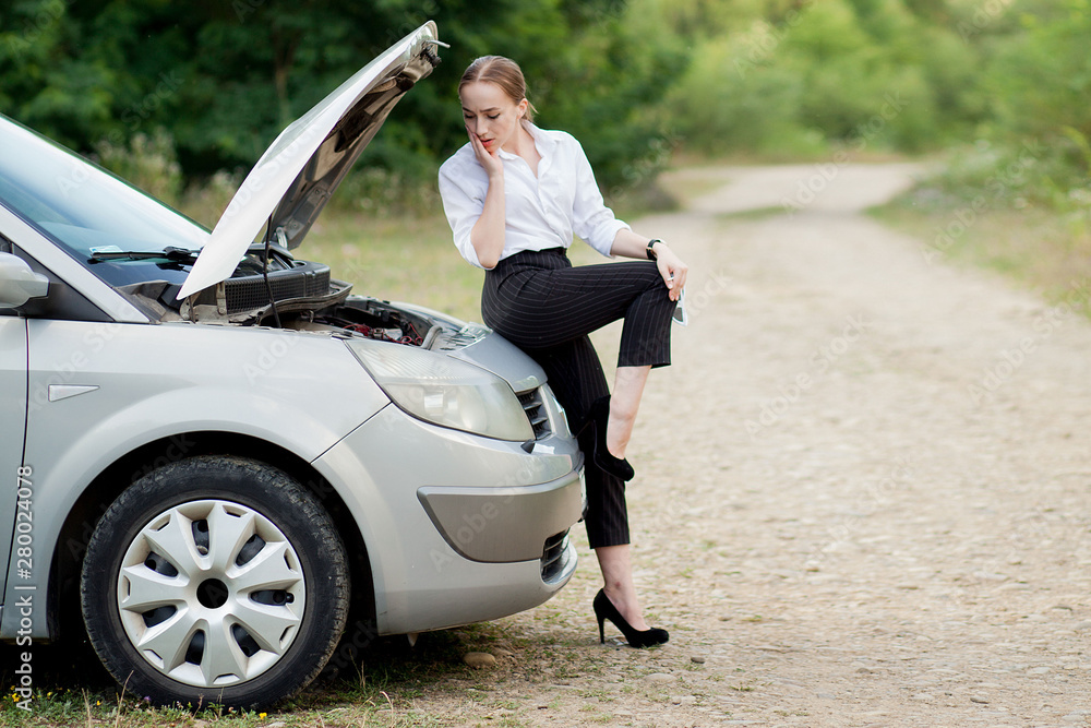 Young woman by the roadside after her car has broken down She opened the hood to see the damage Young woman by the roadside after her car has broken down She opened the hood to see the damage
