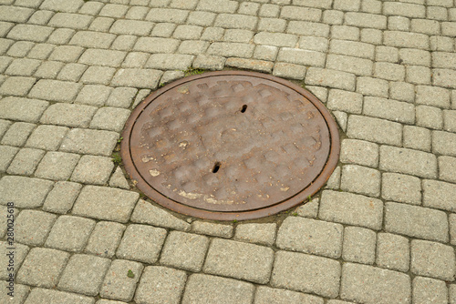 metal manhole with on the sidewalk with a stone walkway