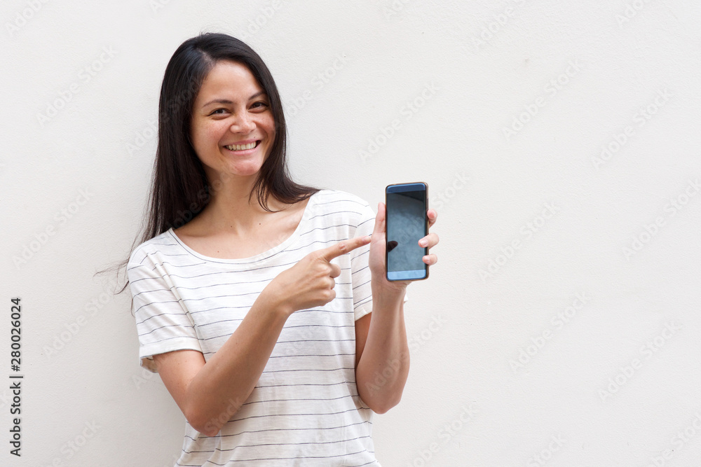 happy young asian woman pointing to mobile phone by white background happy young asian woman pointing to mobile phone by white background