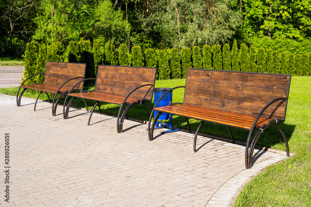wooden bench with iron legs in a park on a sunny day in summer wooden bench with iron legs in a park on a sunny day in summer