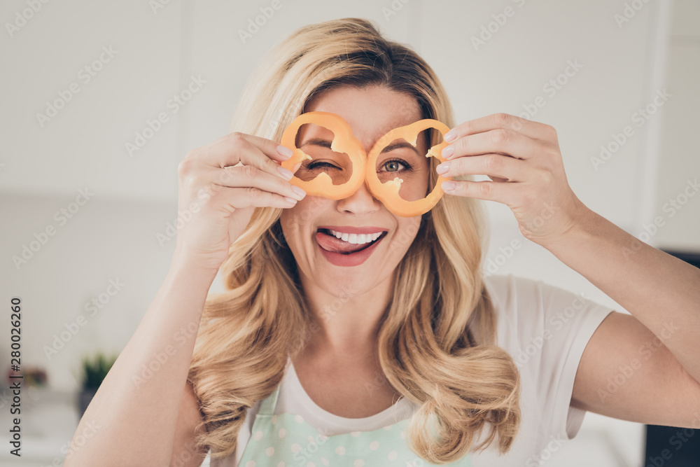 Close-up portrait of her she nice attractive lovely playful careless cheerful cheery wavy-haired lady having fun with orange pepper slices pieces in light white interior kitchen indoors Close-up portrait of her she nice attractive lovely playful careless cheerful cheery wavy-haired lady having fun with orange pepper slices pieces in light white interior kitchen indoors