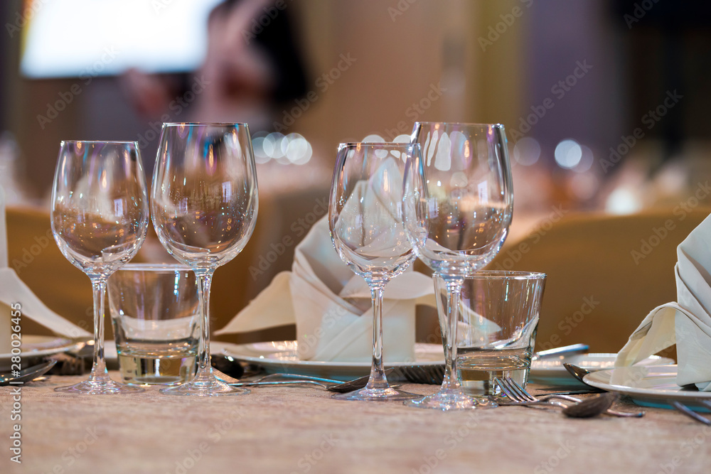 crystal and glass glasses on the served tables for a banquet with color lighting