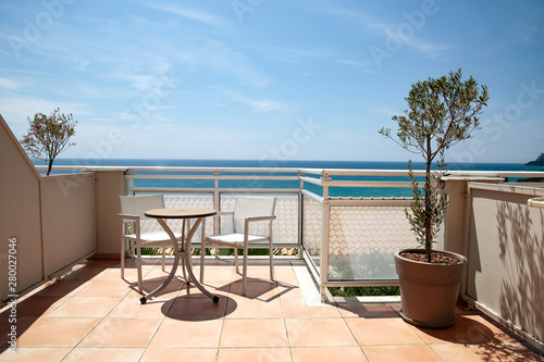 A terrace with table and chairs in a blue sky and ocean view.