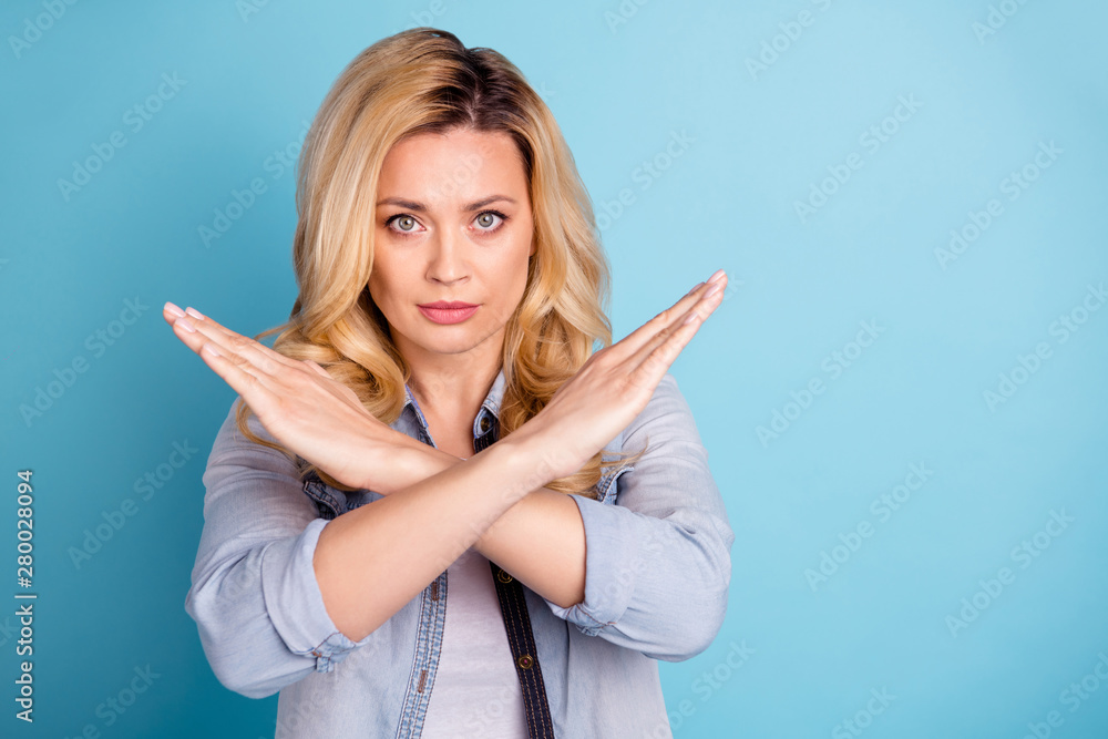 Portrait of strict woman crossing her hands looking at camera isolated over blue background Portrait of strict woman crossing her hands looking at camera isolated over blue background