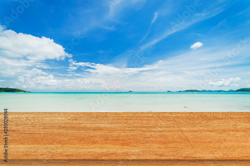 wood table with tropical beach and sea summer and blue sky with cloud background. beautiful floor copy space for design your products brand for ad.