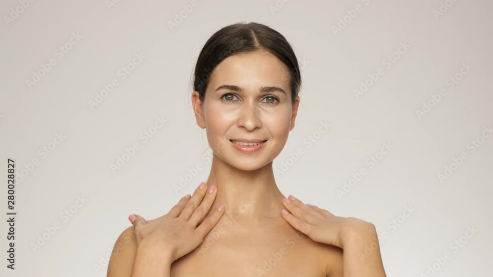 Beautiful girl strokes her neck and hands and smiles close up view slow motion Beautiful girl strokes her neck and hands and smiles close up view slow motion