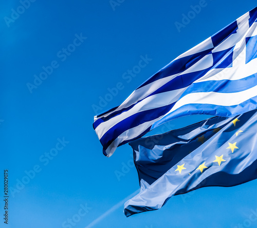 Flags of Greece and European Union on blue sky background, politics of Europe photo