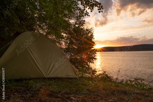Tent on the lake in sunset light. Camping on the lake