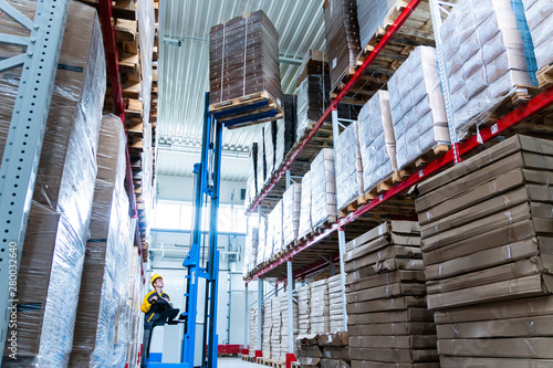 фотографія warehouse worker driver in uniform delivery and loading cardboxes by forklift st