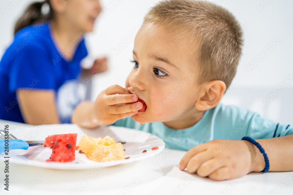 Little boy eating watermelon by the table at home Little boy eating watermelon by the table at home