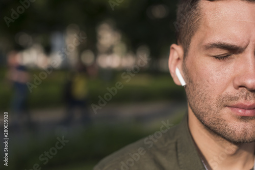 Close-up of man listening music with wireless earphone