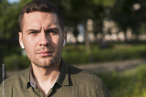 Portrait of serious man wearing wireless earphone looking at camera