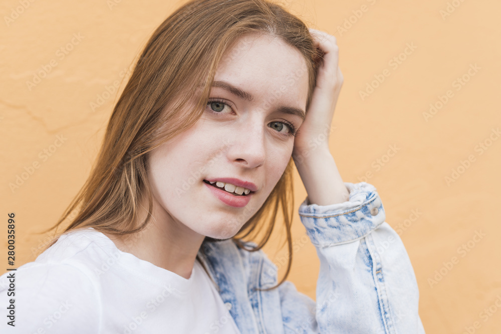 Close-up of attractive young woman looking at camera on beige backdrop Close-up of attractive young woman looking at camera on beige backdrop