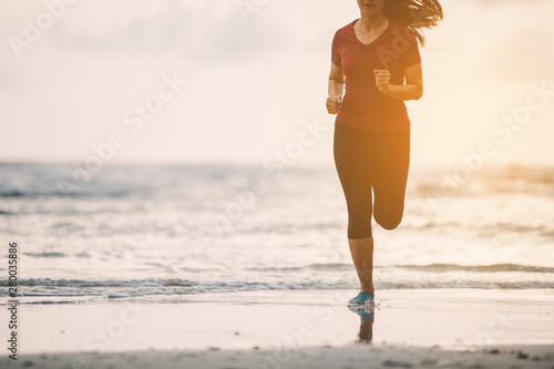 Runners. Young people running on beach. Athletic attractive people jogging on beach enjoying the sun exercising their healthy lifestyle.