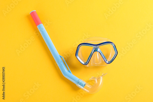 Snorkel and diving mask on yellow background, space for text