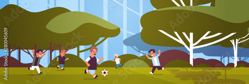 schoolboys playing football elementary school kids having fun with soccer ball on grass sport activities concept landscape background flat full length horizontal
